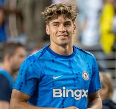 a young man in a blue soccer uniform smiles at the camera while holding a ball