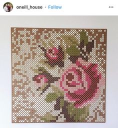 a cross - stitch picture with pink roses on brown and white background, framed in wood frame