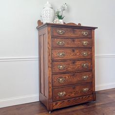 an old wooden chest of drawers in a room with hardwood floors and white walls,