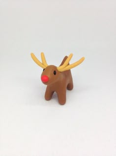 a small toy reindeer with red nose and antlers on it's head, standing in front of a white background