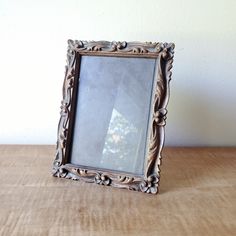 an old wooden frame sitting on top of a table next to a wall mounted mirror