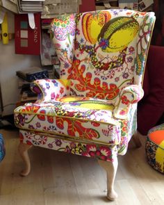 an upholstered chair and foot stool in a cluttered room