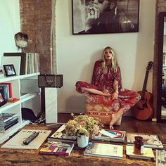 a woman sitting on a chair in front of a table filled with books and magazines