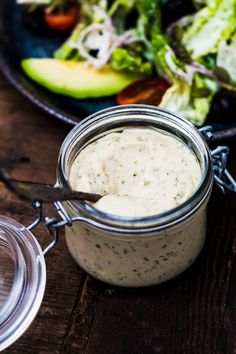 a glass jar filled with dressing next to a salad