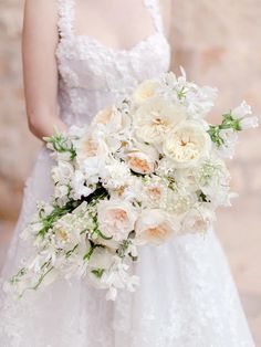 a bride holding a bouquet of white and peach flowers