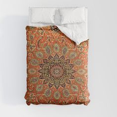 an orange and brown comforter with white pillows on top of it in front of a wall