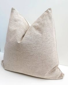 a beige pillow sitting on top of a white table