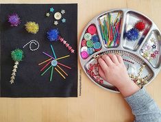 a child's hand is on the tray next to some crafting supplies