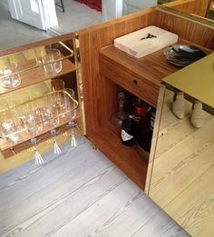 an open cabinet filled with wine glasses and other items on top of a wooden floor