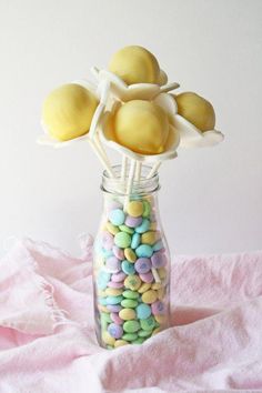 a glass jar filled with yellow and blue candies on top of a pink blanket