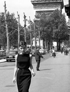 a woman is walking down the street in an old photo