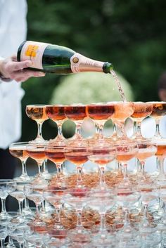 champagne being poured into wine glasses at an outdoor event