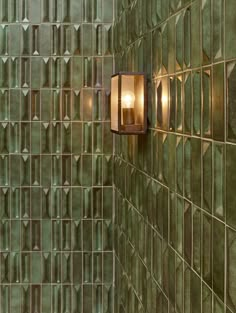 a green tiled wall with two lights on it