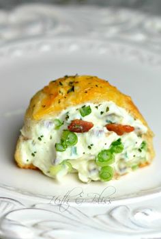 a piece of food that is sitting on a white plate with green onions and peas