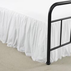 a bed with a white bedspread and black metal rails on top of it