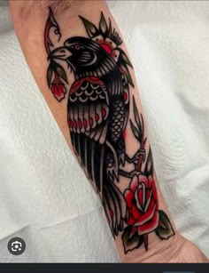 a black bird with red roses on it's arm is shown in this image