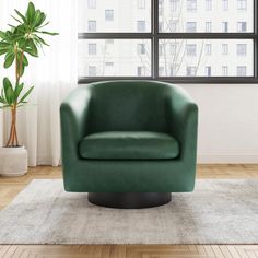 a green chair sitting on top of a wooden floor next to a large potted plant