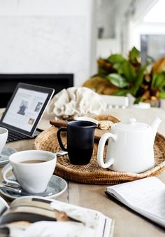 there is a tray with cups and saucers on the table next to a laptop