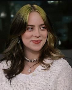 a close up of a person wearing a sweater and necklace with an earring on