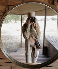 a woman taking a selfie in front of a mirror with her hat and purse