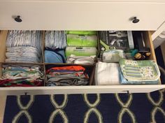 an open drawer with clothes and diapers in it