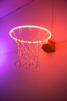 a basketball hoop hanging from the side of a wall with purple lights around it and a red light behind it