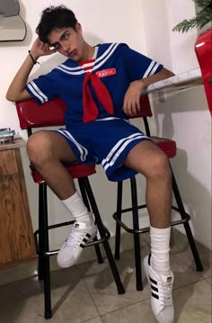 a man sitting in a chair with his foot on the bar stool while wearing a blue and red uniform