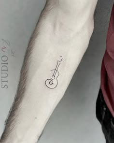 a man's arm with a guitar tattoo on the left side of his arm