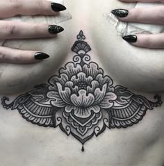 a woman's chest with black and white tattoos on her stomach, showing the intricate design