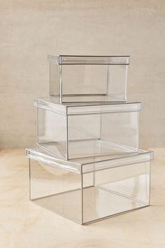 three clear storage boxes stacked on top of each other in front of a beige background