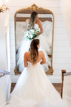 a woman in a wedding dress looking at her reflection in the mirror while she is getting ready to walk down the aisle