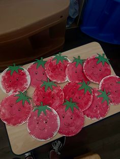 some paper plates with strawberries on them sitting on top of a wooden table in front of a person's feet