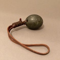 an object with a cord attached to it sitting on a white surface, in the shape of a ball