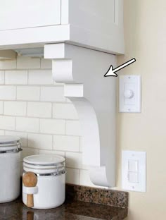 a kitchen counter with two jars on it and an outlet in the wall above them