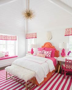 a pink and white bedroom with striped rugs