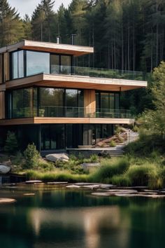 a large house sitting on top of a lush green hillside next to a lake and forest