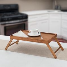 a wooden tray with a cup and saucer sitting on top of it next to an oven