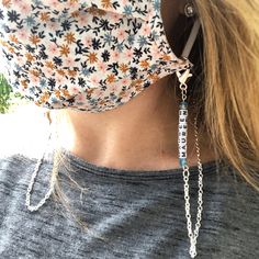 a woman wearing a face mask with a chain attached to it's earring