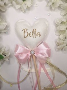 a white heart shaped lollipop with a pink bow and name written on it