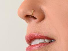 a woman's nose with a gold nose ring on top of her nose and white teeth