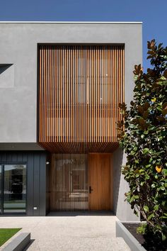 a modern house with wooden slats on the front door and side entrance to it