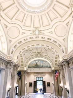 two people are standing in the middle of a large hall with marble floors and ceiling