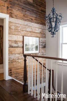 a chandelier hanging from the side of a wooden wall next to a stair case