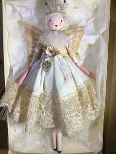 a doll in a box with lace on it