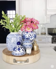 pink flowers are in blue and white vases on a kitchen counter with gold accents