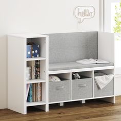 a white bookcase with four bins and a shelf filled with books on top of it