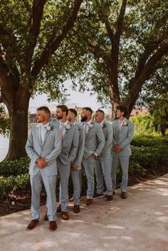 a group of men standing next to each other in front of a tree and water