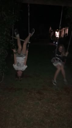 two people on swings in the grass at night