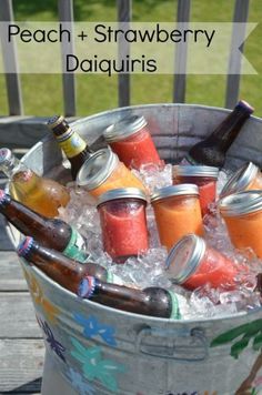 an ice bucket filled with peaches and strawberry daiquiris on top of a wooden table