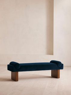 a blue bench sitting on top of a hard wood floor next to a white wall